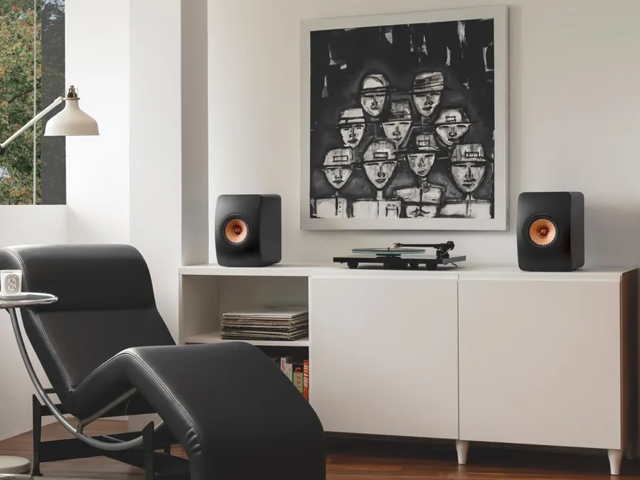 KEF LS50 Wireless II em estante de sala com poltrona